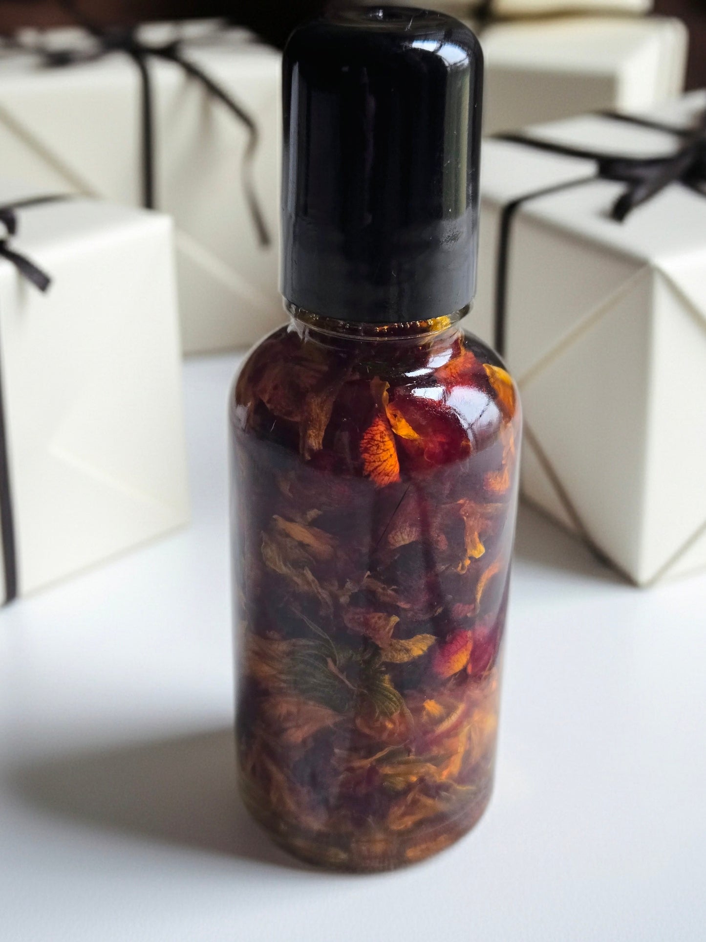 Bottle of Dollhouse Botanicals Red Sea Flora Face Hydrator. Oil with floating calendula and rose petals in glass bottle with black top.