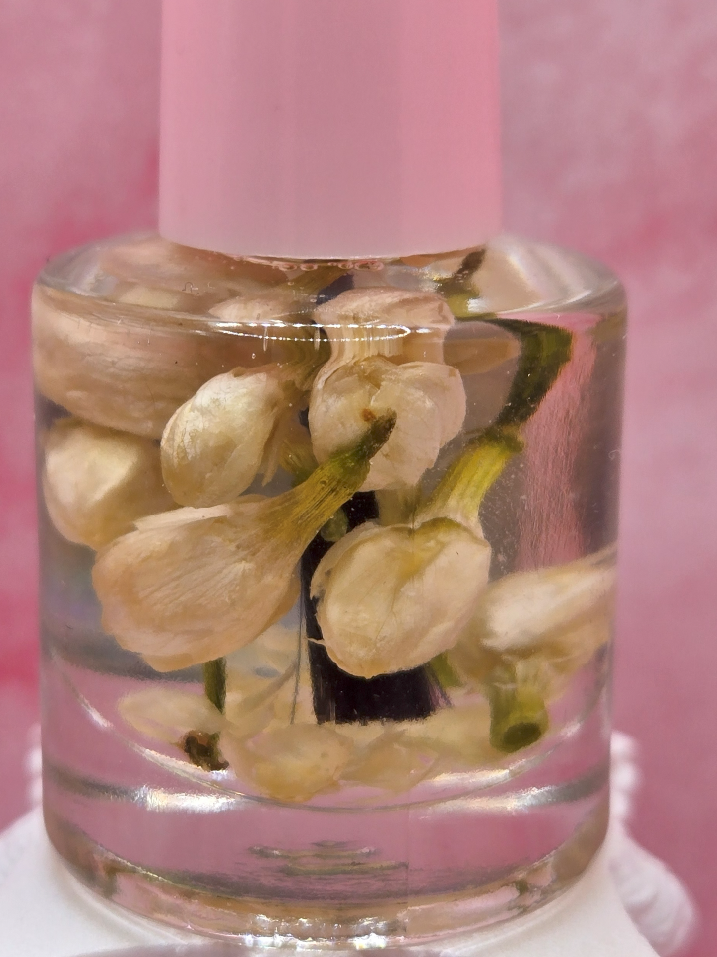 Dollhouse Botanicals Squalane and Jasmine Cuticle Oil with real floating flora in clear glass nail polish bottle with pink top