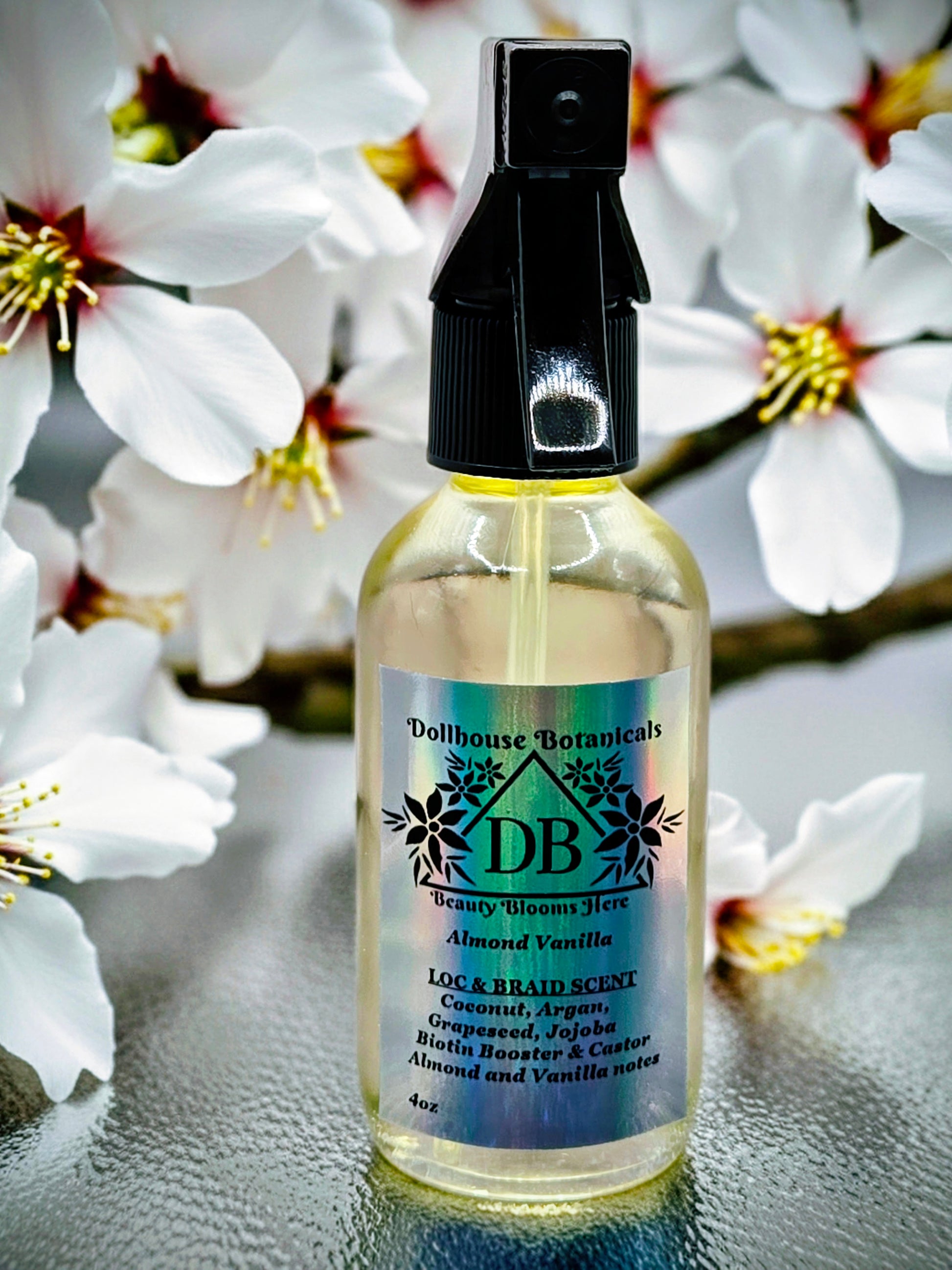 Bottle of Dollhouse Botanicals Loc and Braid Scent. Oil in clear glass bottle with black trigger sprayer applicator. Feminine hair perfume.