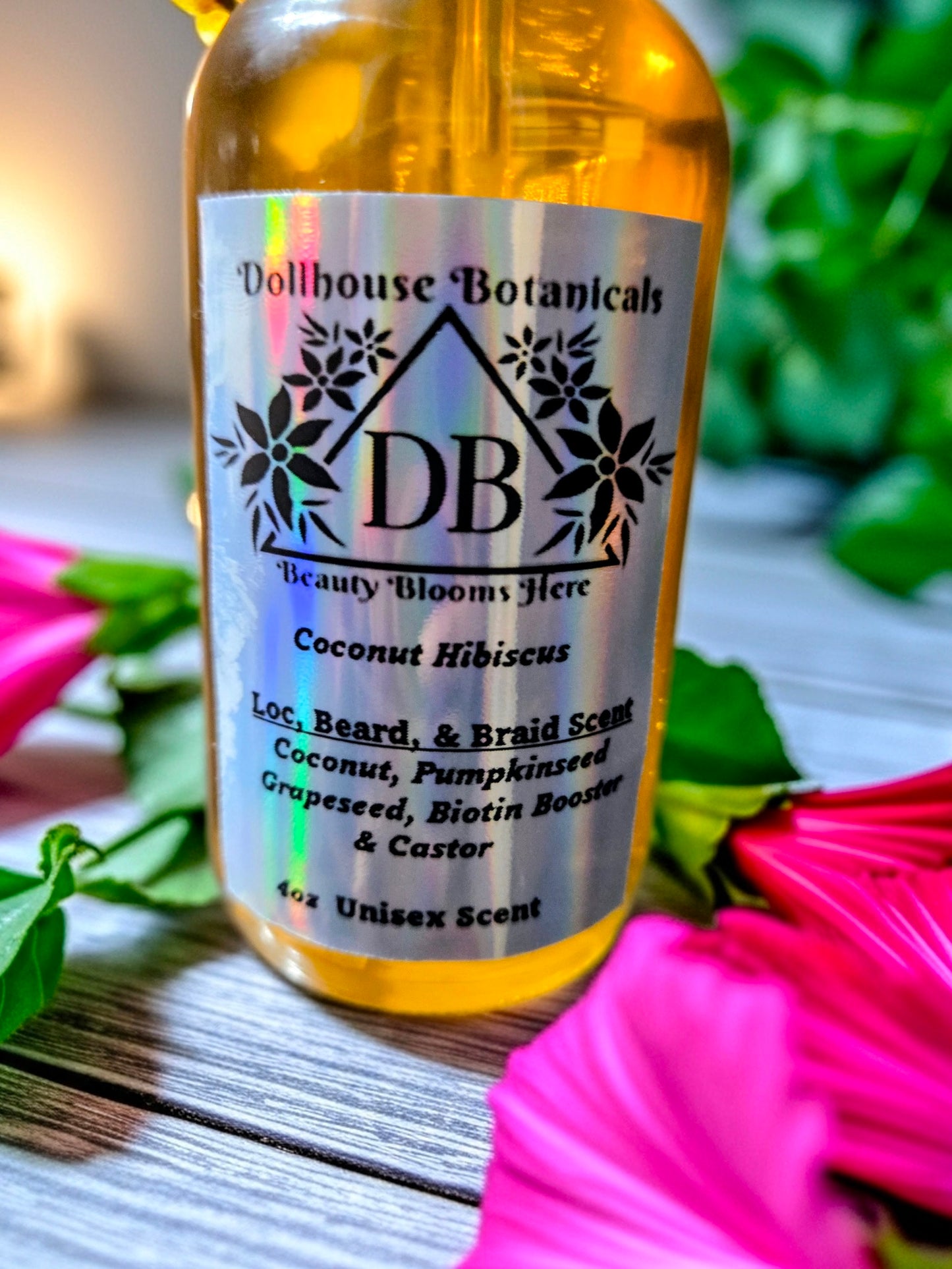 Bottle of Dollhouse Botanicals Coconut Hibiscus Loc, Beard, and Braid Scent. Golden oil in glass bottle. Front facing with label and ingredients displayed. Unisex hair fragrance.