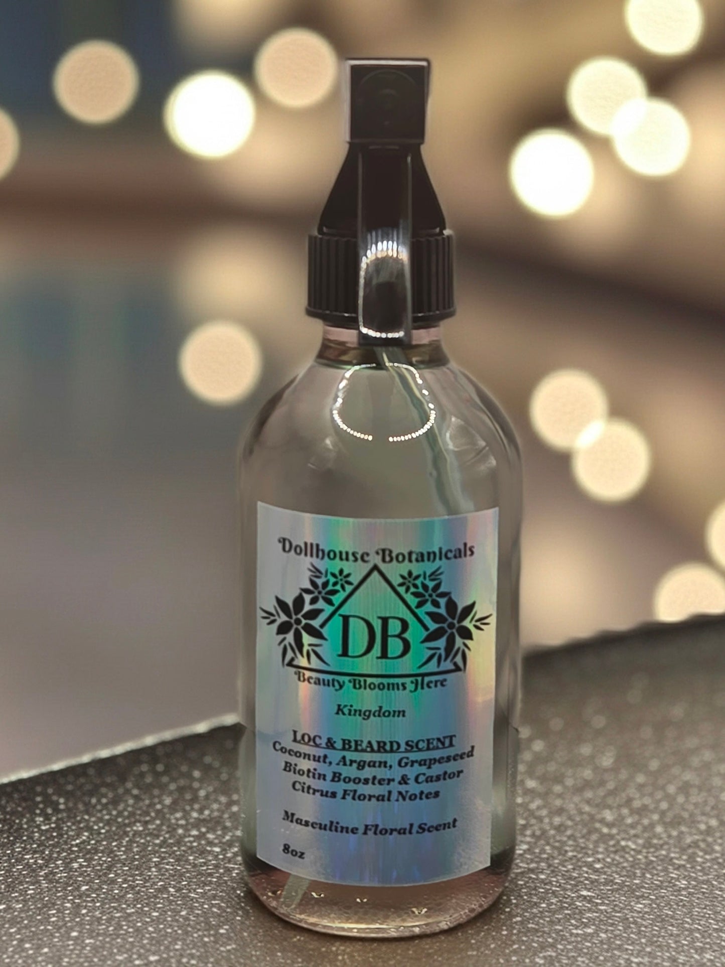 Bottle of Dollhouse Botanicals Kingdom Loc and Beard Scent. Clear oil in bottle with black trigger sprayer applicator. Masculine Scent.