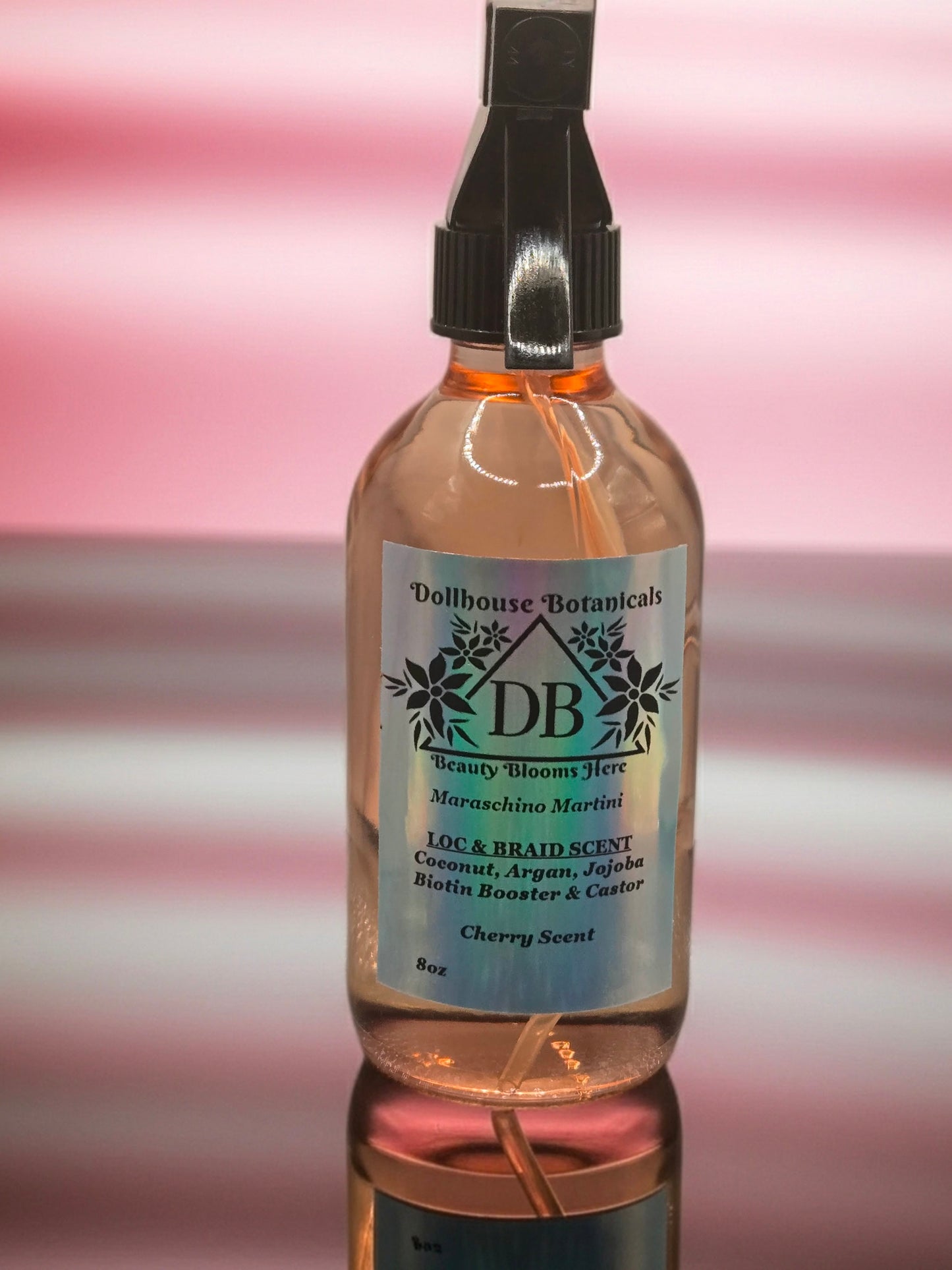 Bottle of Dollhouse Botanicals Maraschino Martini Loc and Braid Scent. Oil in glass bottle with trigger sprayer. Feminine hair fragrance. Front facing with ingredients displayed.