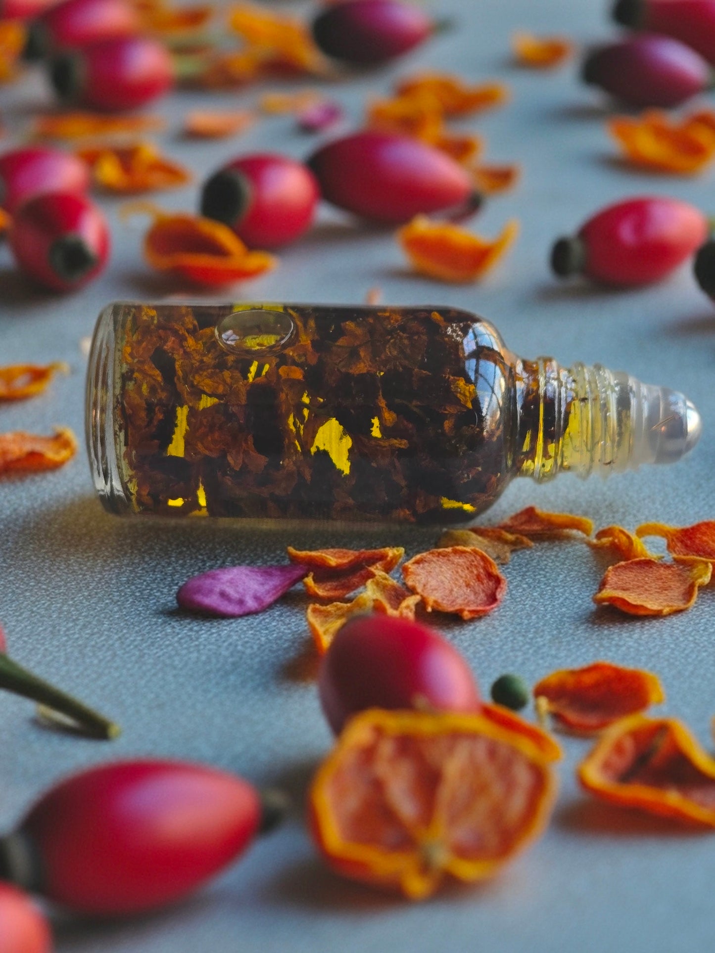 Bottle of Dollhouse Botanicals Moonlight Flora Face Hydrator. Golden oil with floating dried snow chrysanthemum in glass bottle with steel roller ball applicator.